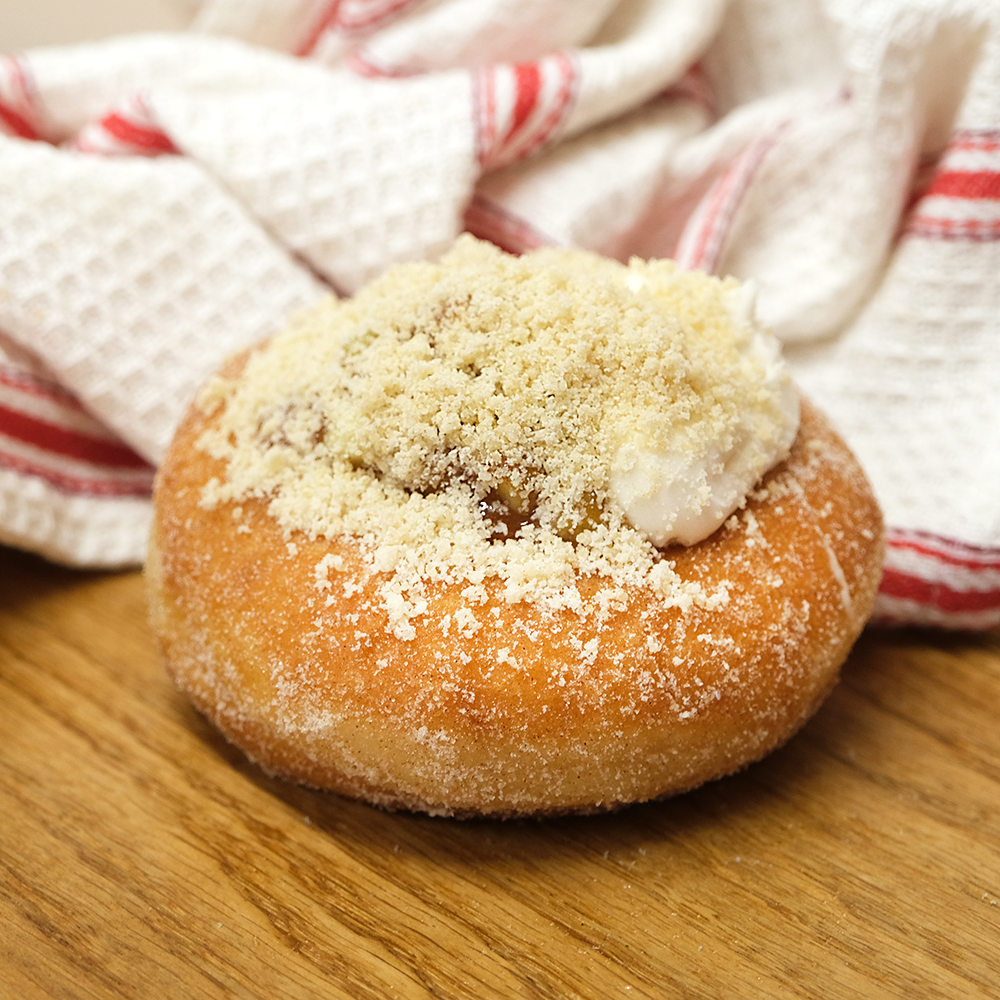 A large apple doughnut with a crumble topping made in a bakery in Newbury